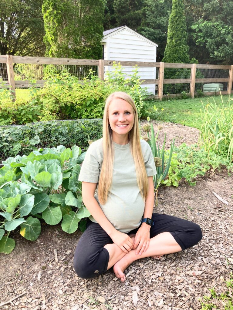 pregnant woman sitting bare foot in her vegetable garden