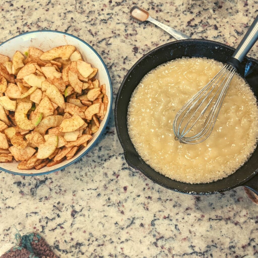 cast iron skillet with apple pie filling inside next to a bowl filed with cinnamon apple slices