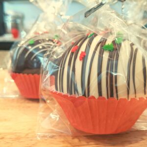 hot chocolate bombs in cellophane bags inside cupcake liners on top of a wooden cutting board