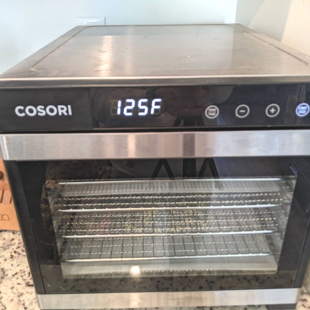 cosori dehydrator set at 125 degrees f with minced garlic inside