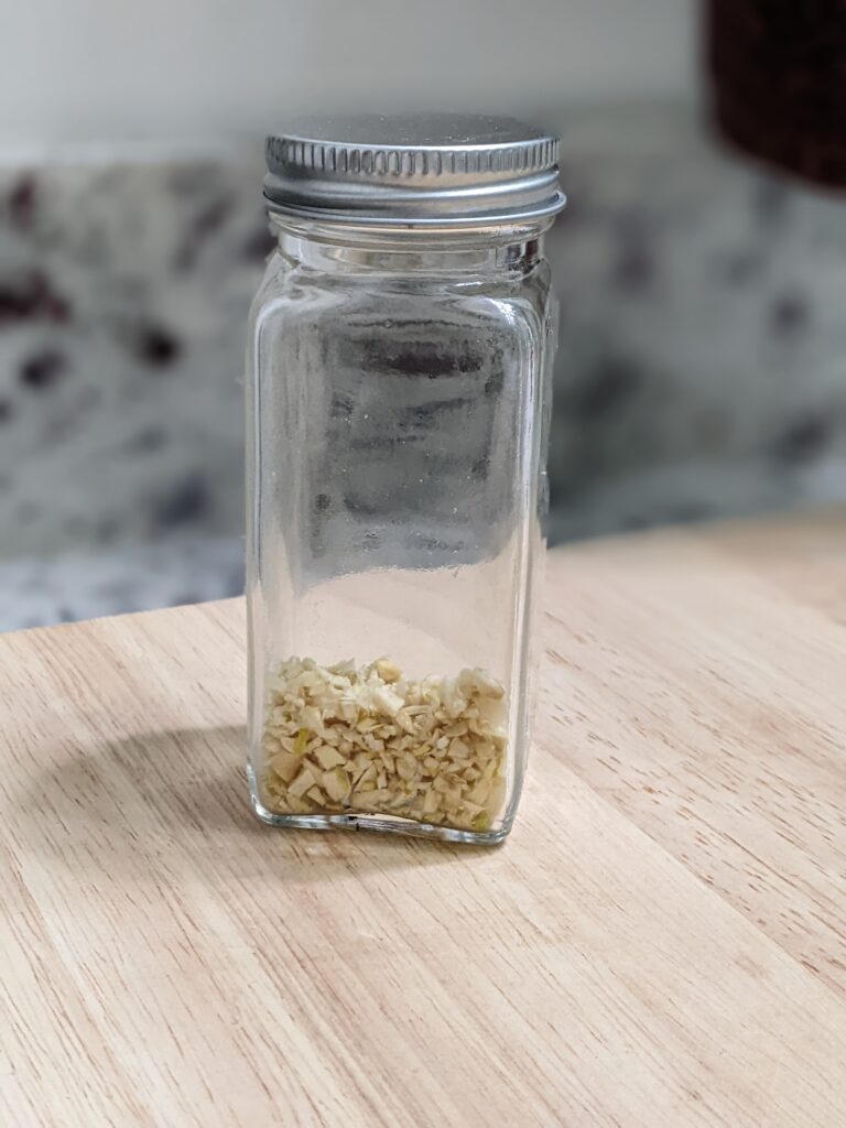 dehydrating garlic in a airtight jar on top of a wooden cutting board