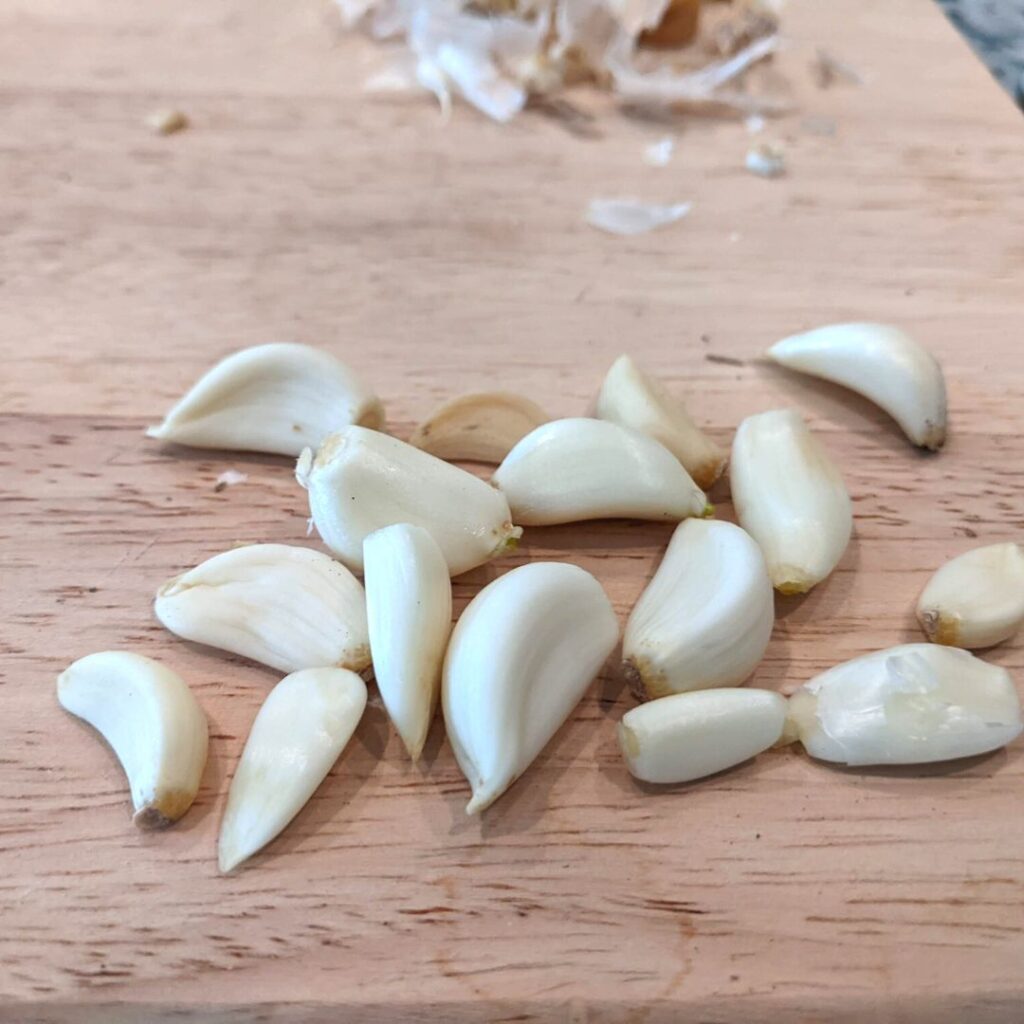 peeled garlic on a wooden cutting board